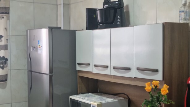 A kitchen with a refrigerator, microwave, and cabinets. - Kitnet na Cidade Ocian / Praia Grande (Praia Grande)