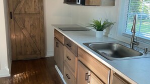 Una cocina con armarios de madera, un lavamanos de acero inoxidable y una puerta corrediza de estilo rústico.