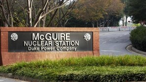 A sign for McGuire Nuclear Station, Duke Power Company, with a road and trees in the background.