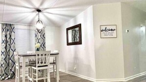 A dining area with a wooden table and chairs, a ceiling fan, and a 'welcome' sign on the wall. - Spacious & Inviting Home in Denver, NC (Denver)