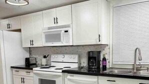 A modern kitchen with white cabinets, a microwave, stove, and dishwasher. - Spacious & Inviting Home in Denver, NC (Denver)