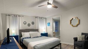 A bedroom with a bed, bedside tables, a desk, a chair, a ceiling fan, and a mirror on the wall. - Spacious & Inviting Home in Denver, NC (Denver)
