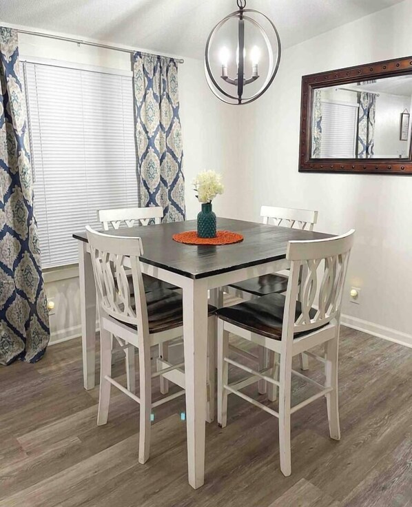 A dining area with a round table, white chairs, a vase with flowers, a chandelier, and a mirror on the wall. - Spacious & Inviting Home in Denver, NC (Denver)