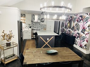 Una cocina moderna con armarios blancos, encimera negra y diseño de papel tapiz floral.