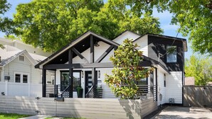 Une maison moderne à deux étages, dotée d’un porche couvert, d’un petit jardin devant et d’une clôture en bois.