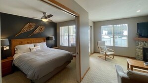 A bedroom with a bed, nightstands, a ceiling fan, and a fireplace. - Creekside condo w/full kitchen, gas fireplace, close to trails & village (Silver Star Mountain)
