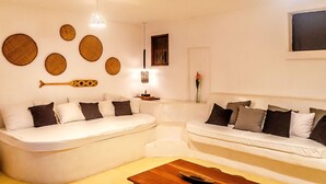 Un salon moderne avec deux canapés blancs, une table basse en bois et des œuvres d’art décoratives accrochées au mur.