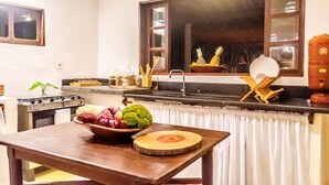 Une cuisine avec une table en bois, un saladier rempli de fruits et un poêle.