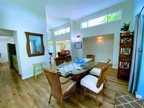 A dining area with a glass table, wicker chairs, and a wooden floor.
