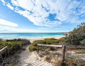 A sandy beach path leading to a coastal area with a wooden fence and greenery. - Spacious Home with Pool, Ebikes and Beach Gear! (Sarasota)