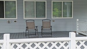 A covered porch with two chairs and a white picket fence. - COZY, BEAUTIFUL APARTMENT AT AVANTI COVE (Conneaut Lake)