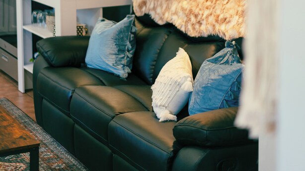 A modern living room with a black leather sofa, a wooden coffee table, and a hanging woven light fixture. - COZY, BEAUTIFUL APARTMENT AT AVANTI COVE (Conneaut Lake)