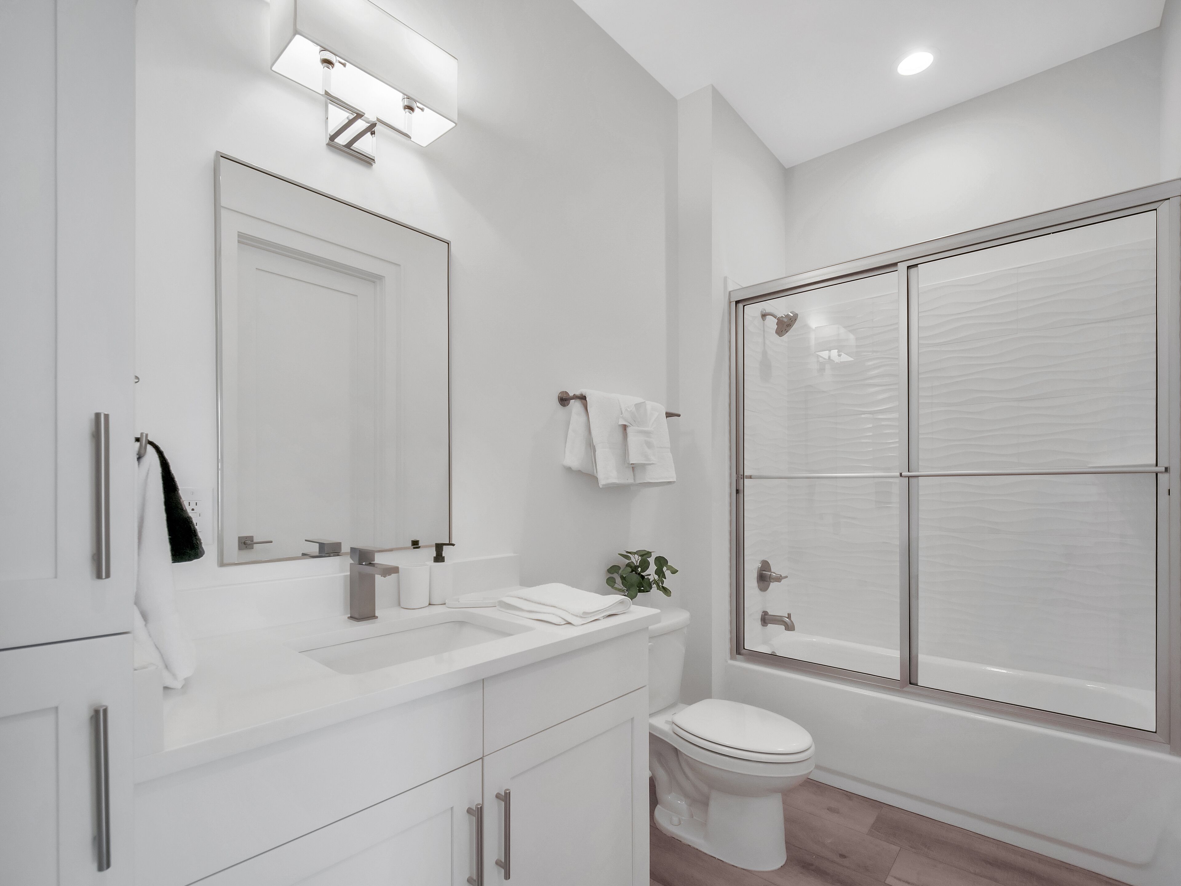 Une salle de bain moderne avec un grand miroir, un lavabo, des toilettes et une douche à l’italienne.