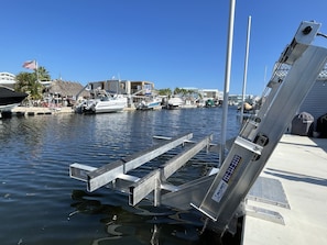 A marina with boats docked, a metal structure, and buildings in the background.