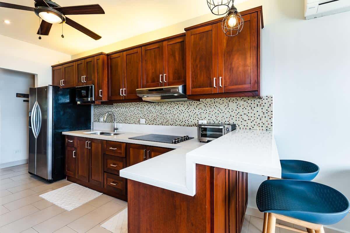 A modern kitchen with wooden cabinets, a stainless steel refrigerator, a built-in oven, and a microwave.