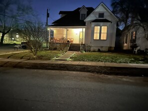 Une maison à deux étages avec un porche à l’avant, un petit jardin et une allée.