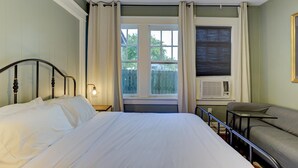 Un dormitorio con cama, ventana con cortinas, calefactor y sofá.