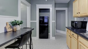 Una cocina moderna con un refrigerador negro, un microondas y un comedor con mesa y sillas.