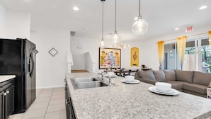 A modern kitchen with granite countertops, stainless steel sink, and black refrigerator. - Private Views & Theme Rooms, Perfect for Families! (Davenport)