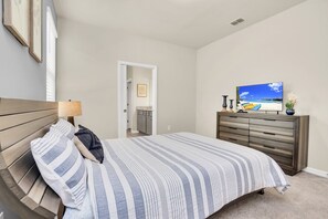 Ein Schlafzimmer mit einem Bett, einem Schminktisch, einem Fernseher und einer Tür zu einem Badezimmer.