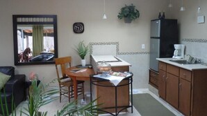 Una cocina compacta con comedor, refrigerador, cafetera y una planta en maceta.