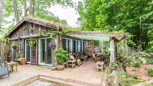 Una cabaña rústica con un patio, mobiliario exterior y un jardín.