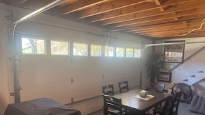 A garage with a dining table, chairs, and a covered car.