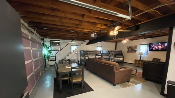 A modern living room with a wooden ceiling, a sofa, a dining table, and a TV.