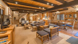 A spacious living area with wooden furniture, a dining table, and a kitchen in the background. - Musketeer by Avantstay Family Friendly Home In Tahoe Swiss Village! (Homewood)