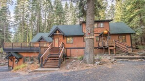 A lodge with a wooden exterior, a covered porch, and a staircase leading to the main entrance. - Musketeer by Avantstay Family Friendly Home In Tahoe Swiss Village! (Homewood)
