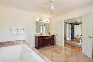 A spacious bathroom with a large bathtub, a vanity with a mirror, and a ceiling fan. - Crawdad by Avantstay Isle of Palms Home w/ BBQ (Isle of Palms)