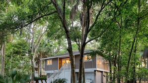 A two-story house surrounded by dense trees and a well-maintained lawn. - Crawdad by Avantstay Isle of Palms Home w/ BBQ (Isle of Palms)