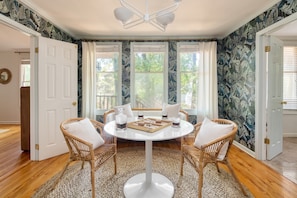 A dining area with a round table, four wicker chairs, and a white rug. - Crawdad by Avantstay Isle of Palms Home w/ BBQ (Isle of Palms)