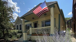 Ein zweistöckiges Haus mit Veranda, Flagge und Treppe.