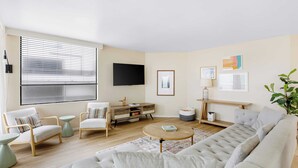 Una sala de estar moderna con un sofá, sillones, una mesa de centro y un televisor.