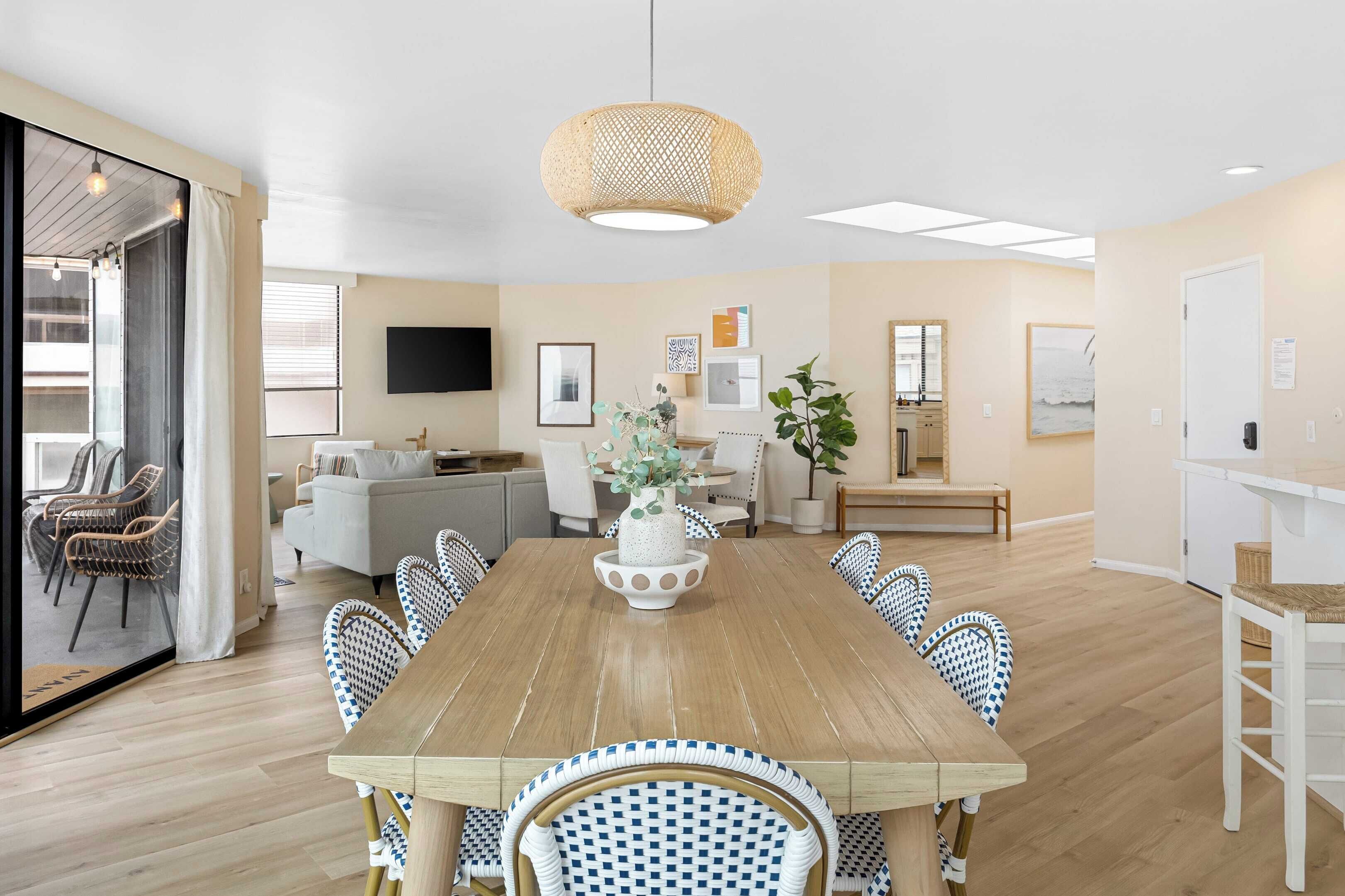 Een moderne eetruimte met een houten tafel, blauw-witte gestreepte stoelen en een centrale vaas met bloemen.