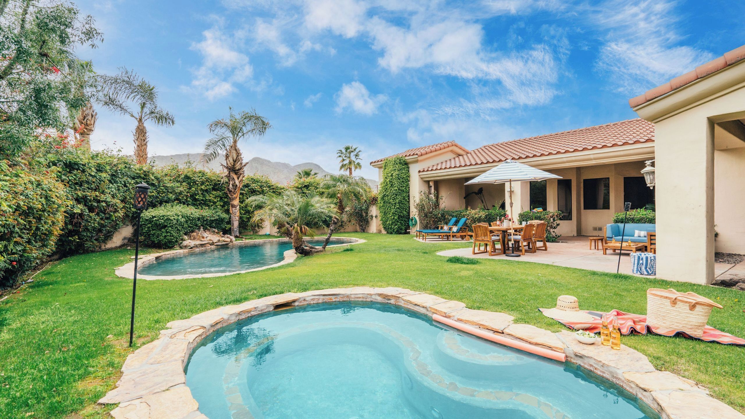 A backyard with a swimming pool, patio furniture, and a covered outdoor seating area.