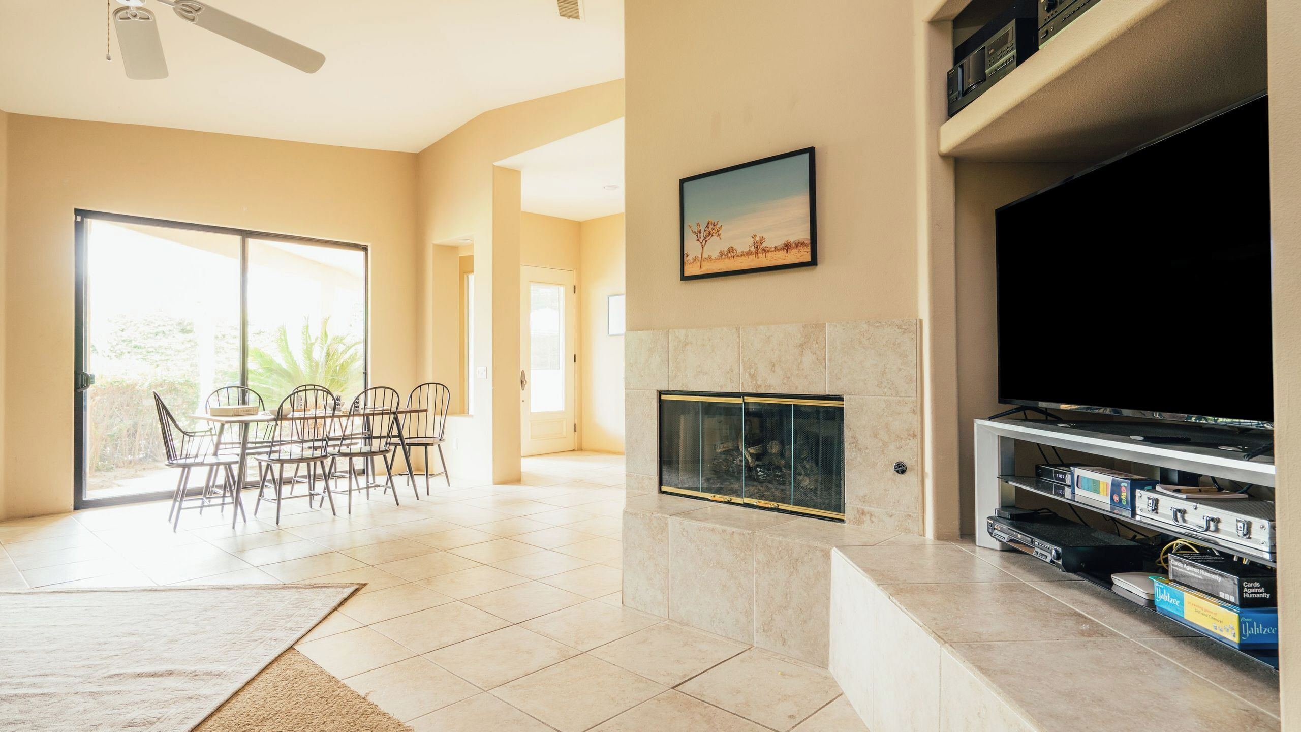 A living room with a fireplace, a television, and a dining area with chairs.