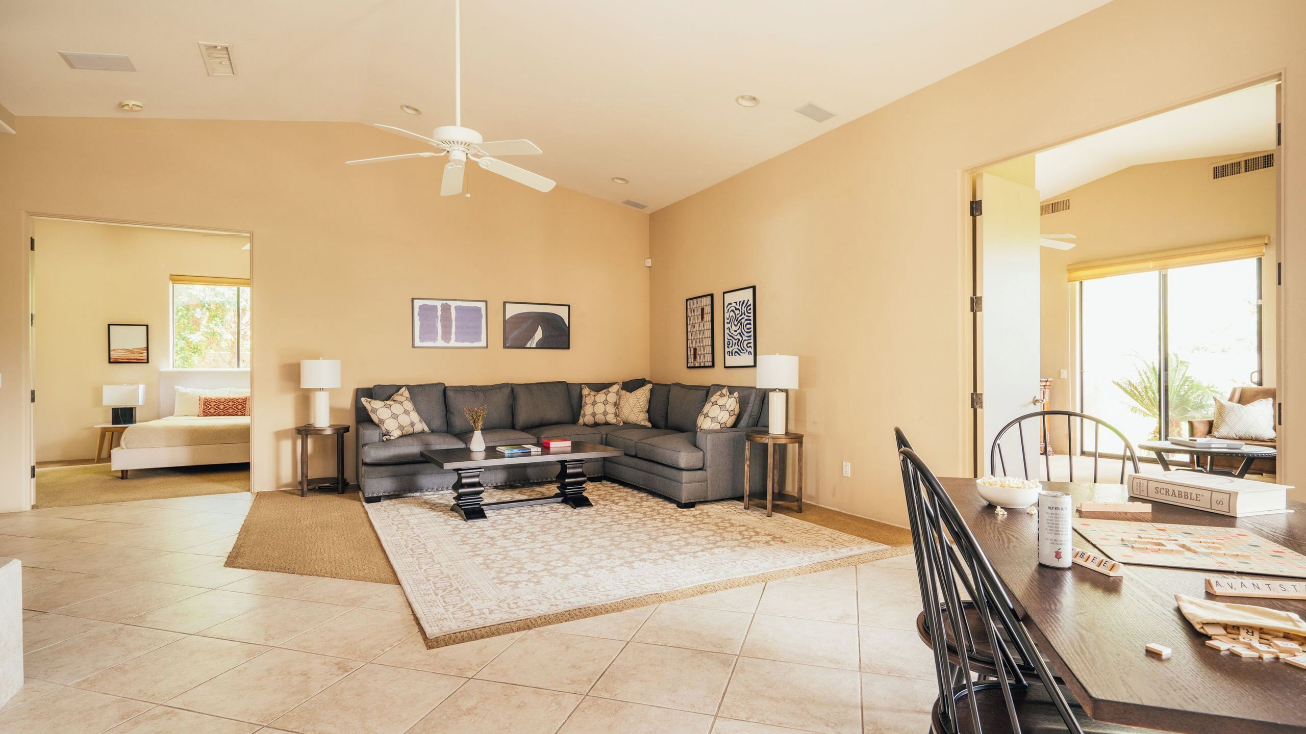 A spacious living room with a sectional sofa, a coffee table, and a dining area with Scrabble tiles.