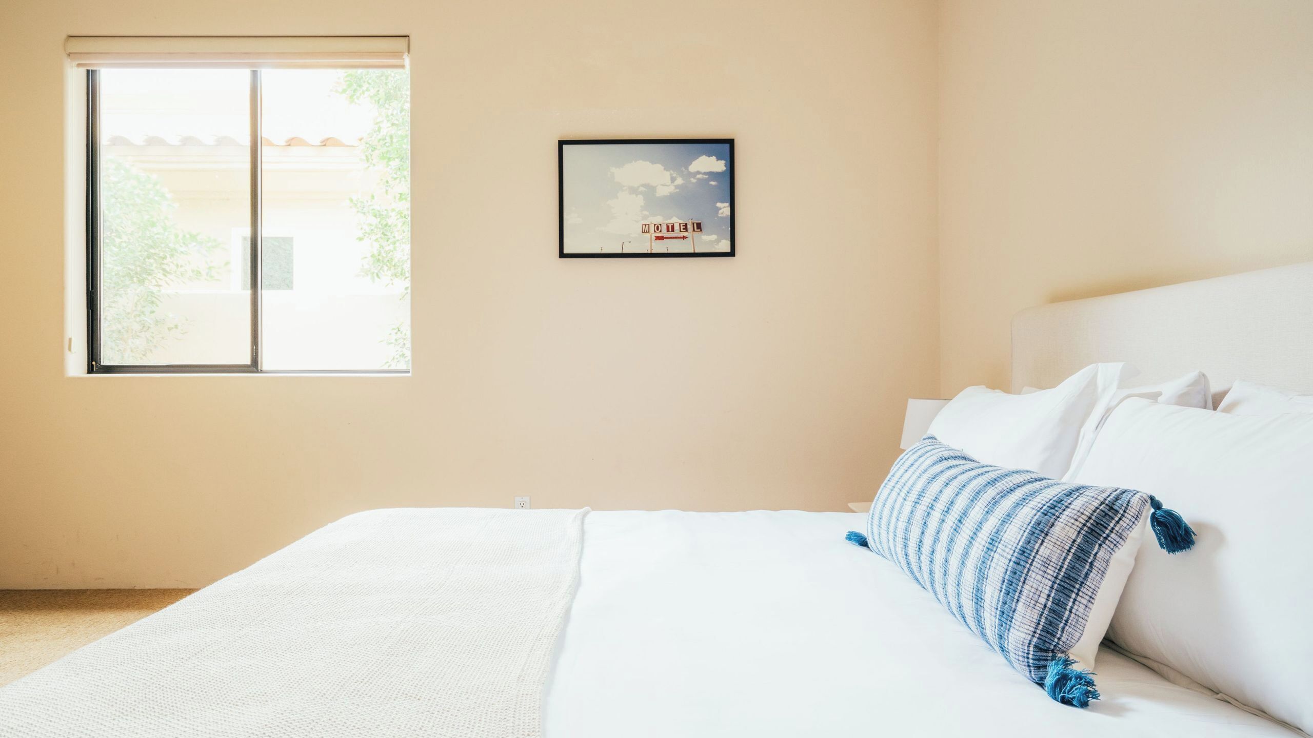 A bedroom with a bed, a window, and a framed picture on the wall.