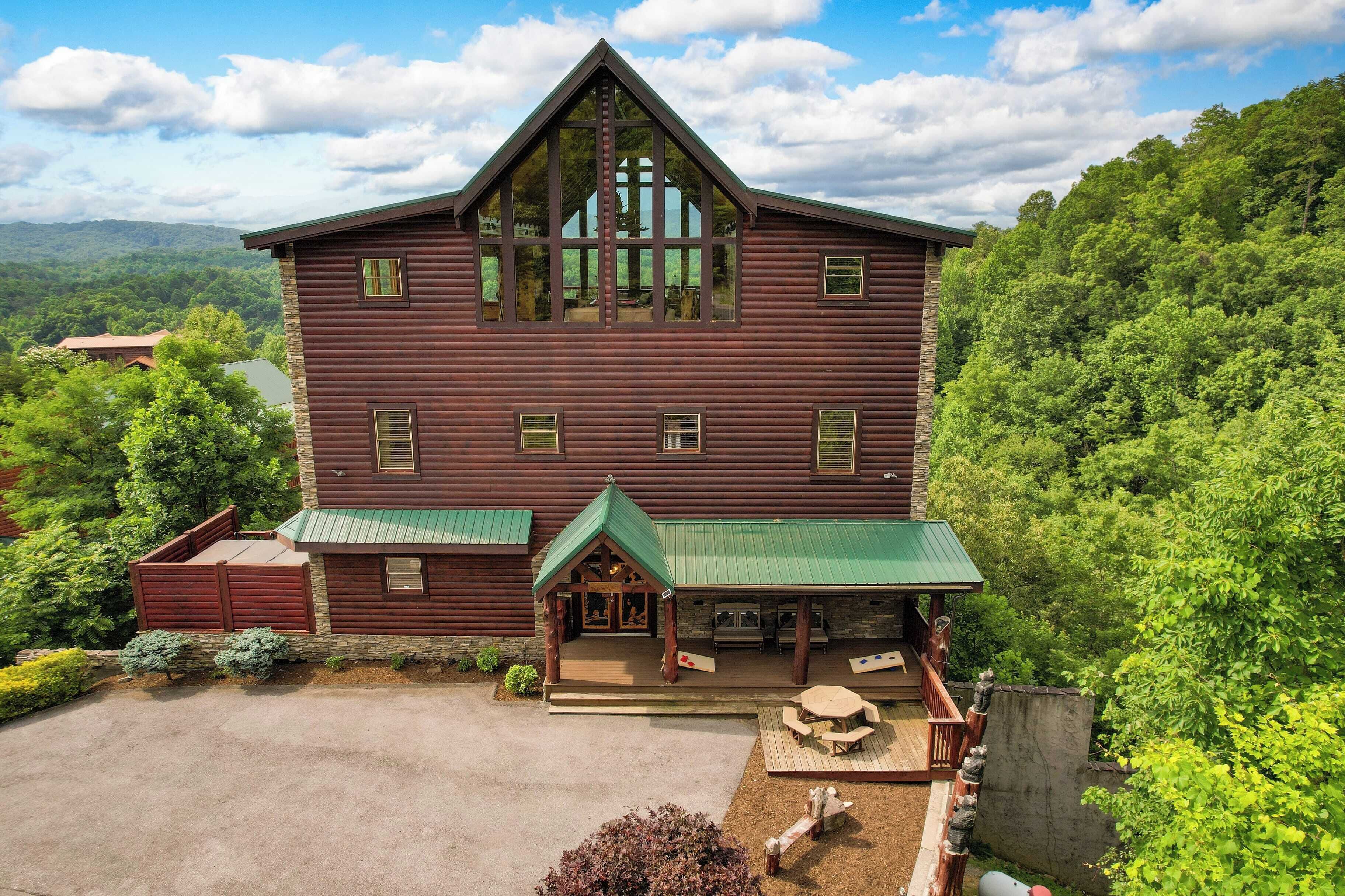 A large log cabin with a green roof, a porch, and outdoor seating.