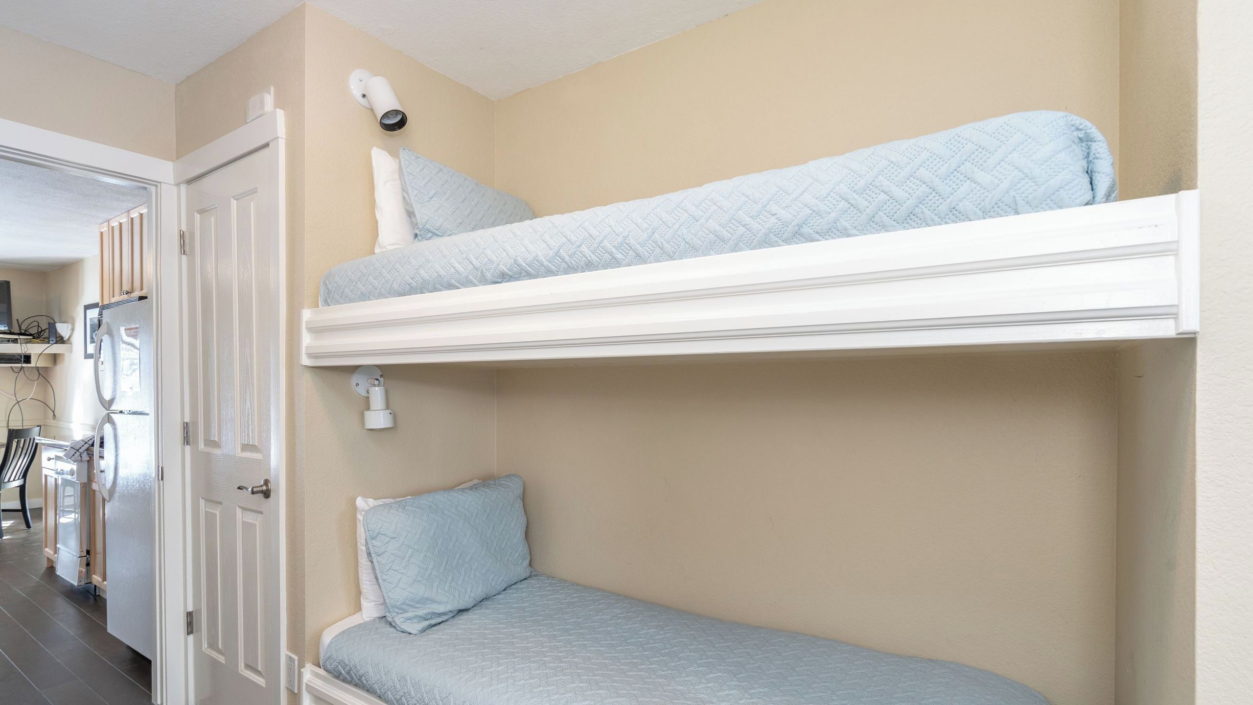 Una cama litera con una cama inferior, una puerta y un aplique fijado a la pared.