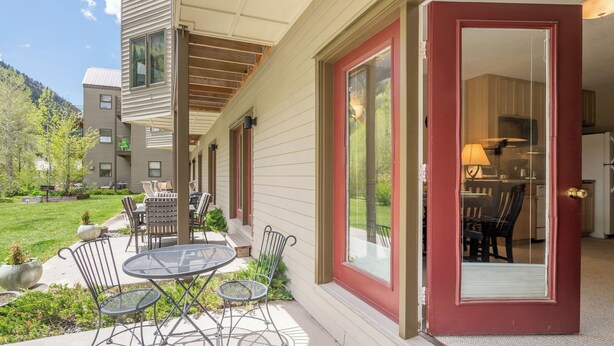 A covered patio with outdoor furniture, a glass door leading to a kitchen, and a view of a mountain. - Viking Lodge 117 by Avantstay Ski Home, Near Town Park & Downtown (Telluride)