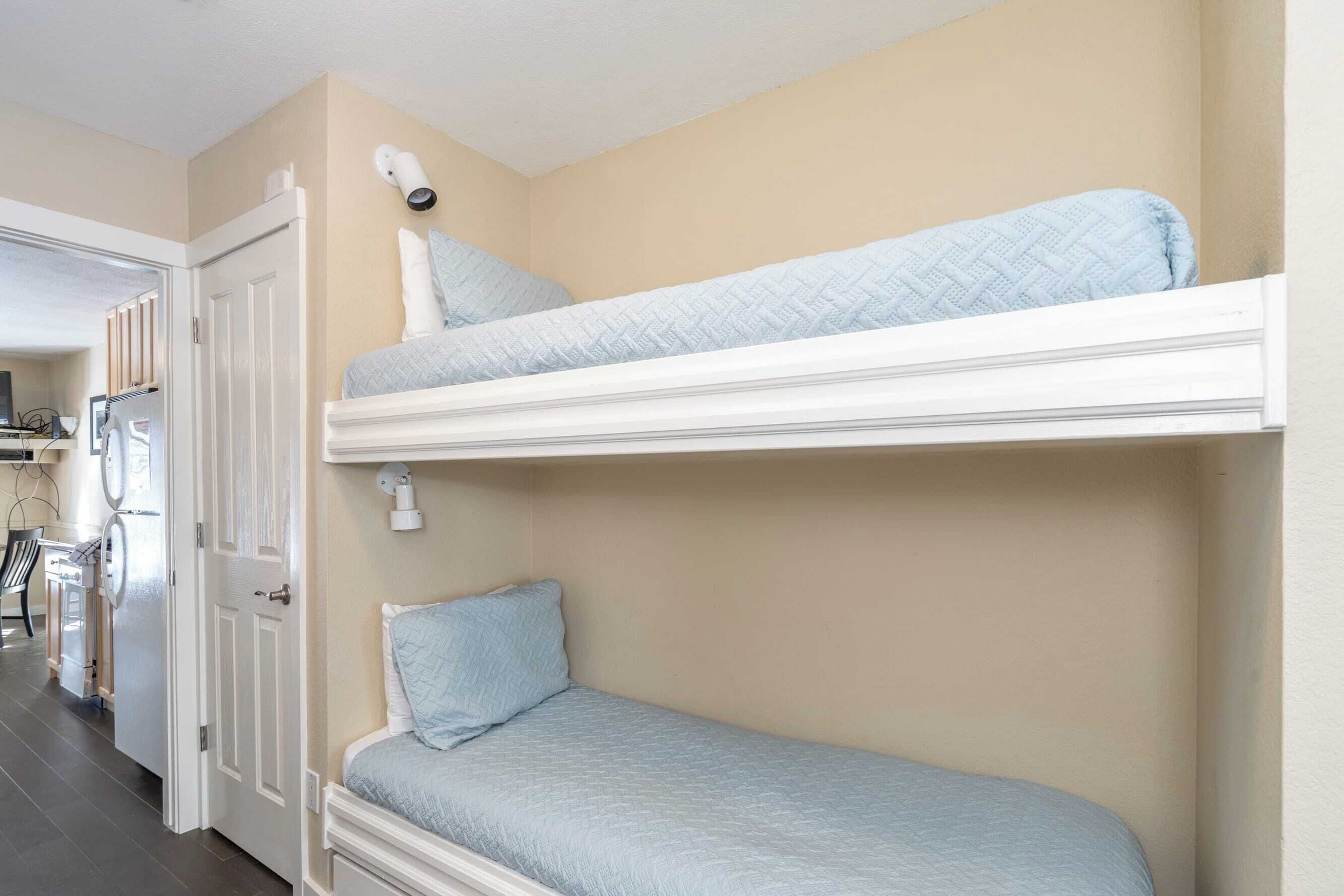 Ein Zimmer mit Etagenbetten, einer Tür, einem kleinen Tisch und einem Stuhl.