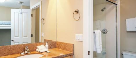 A bathroom with a sink, mirror, towel rack, and a glass shower enclosure.