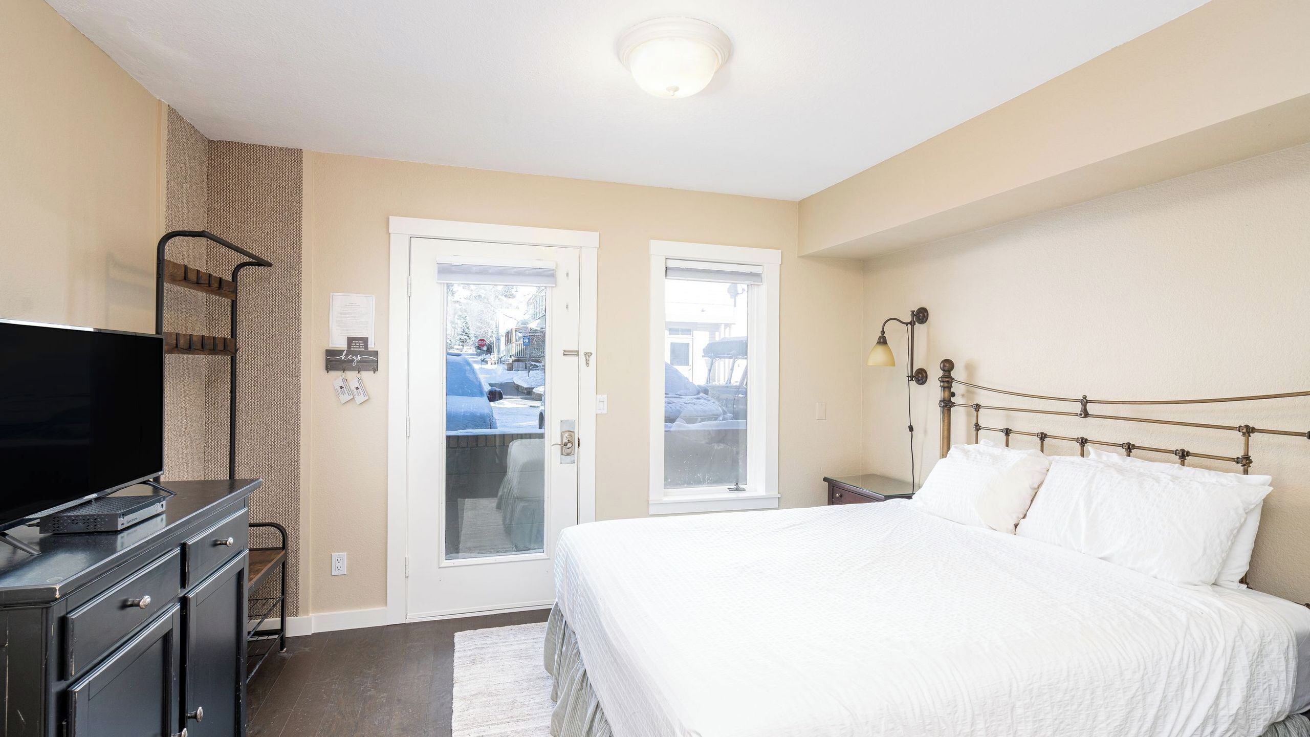 A bedroom with a bed, a television, a desk, and a lamp.