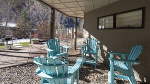 Katettu terassialue, jossa on useita Adirondack-tyylisiä puutarhatuoleja.