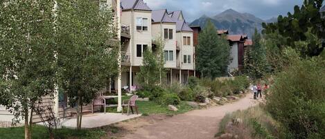 Um bairro residencial com vários edifícios de dois andares, um caminho de terra e vegetação.