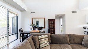 A modern living room with a brown sofa, a dining table with chairs, a large mirror, and a dark wooden cabinet. - Ivory II By Avantstay Gorgeous Spacious Home w/ Views Close To Old Town (Scottsdale)