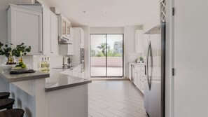 A modern kitchen with white cabinetry, a large island, and a view to a balcony. - Ivory II By Avantstay Gorgeous Spacious Home w/ Views Close To Old Town (Scottsdale)